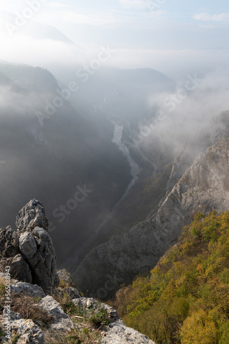 Mountain viewpoint over river canyon obscured in fog and clouds during autumn morning, misty mountain landscape
