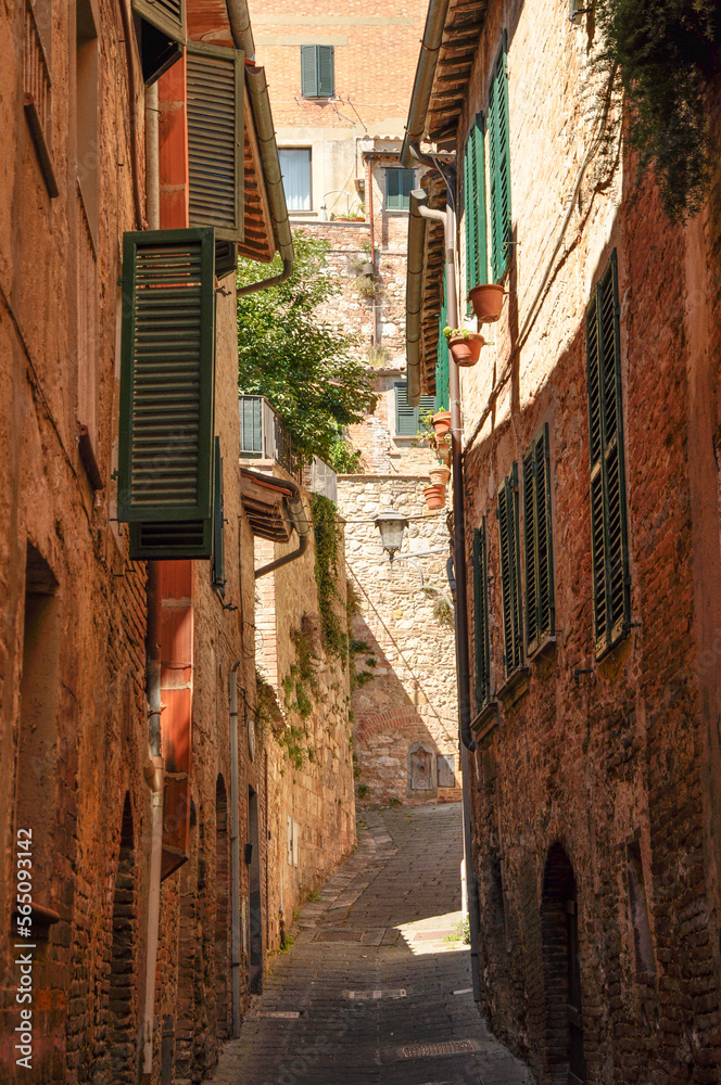 narrow graded brick alley with green shutters in Assisi