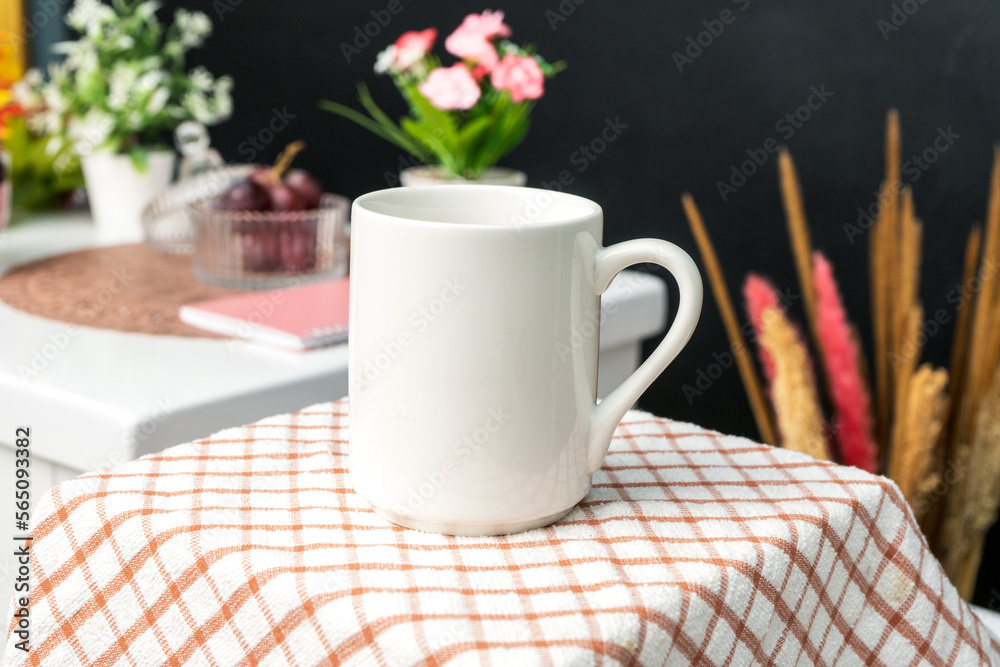 A white blank coffee mug on the top of a hand cloth with simple decorations arranged around it