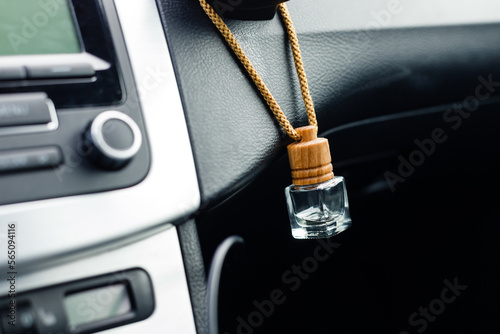 Small aroma glass jar car air freshener hanging on dashboard in vehicle saloon. photo