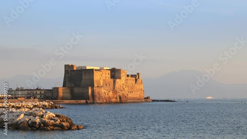Naples, Italy. View from Via Partenope of the Castel dell'Ovo towards the late afternoon. In the background a ship sails in the gulf of Naples on the backdrop of the Sorrento peninsula. 2023-01-03. photo