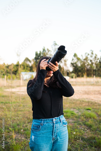 Young unrecognizable amateur photographer woman taking pictures to the sky with a telephoto lens.