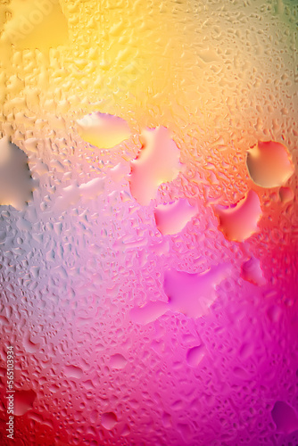 Abstract background. Abstract blur image of yellow and pink soft gradients and highlights through wet glass. Texture of water drops on frozen glass