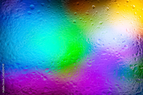 Abstract background. Abstract blur image of colored soft spots of gradients and glare through wet ice glass. Texture of water drops on frozen glass