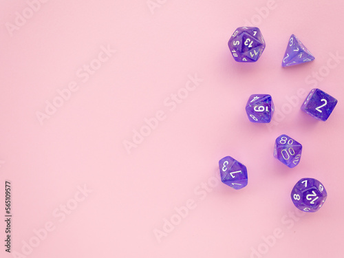 Violet rpg dice on a pink background with space for text