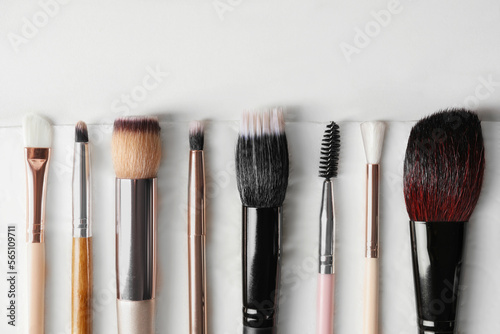 Set of different makeup brushes drying after cleaning on white table, flat lay. Space for text