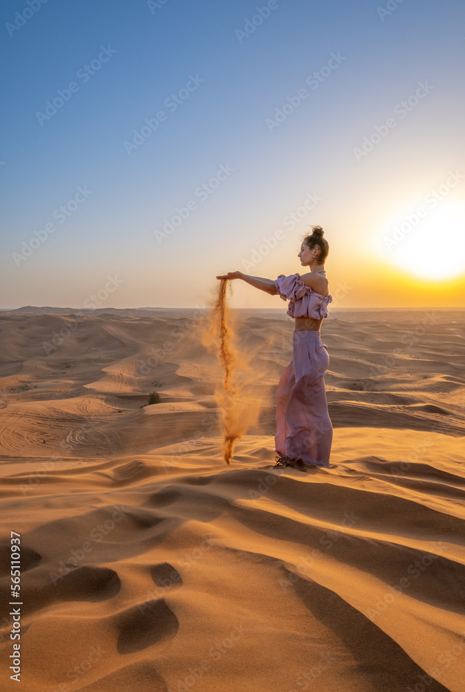 Fototapeta premium A woman dressed like a princess in a desert during sunset. Dubai, UAE.