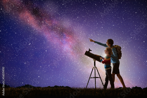 Man and child looking at stars through telescope photo
