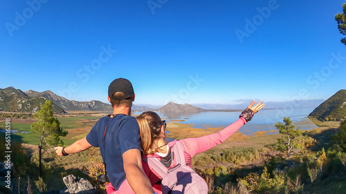 Rear selfies view of couple looking at scenic view of Lake Skadar National Park in autumn seen from Virpazar, Bar, Montenegro, Balkans, Europe. Stunning travel destination in Dinaric Alps near Albania photo