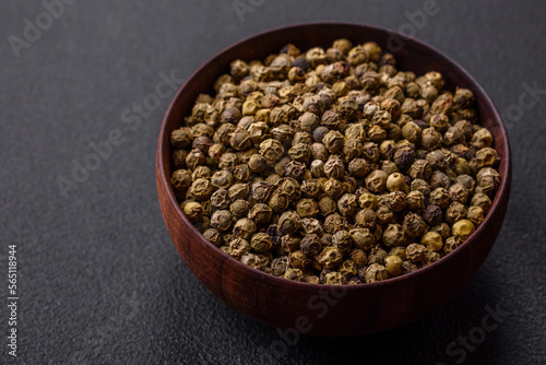 Spice, allspice green in a wooden bowl on a black concrete background