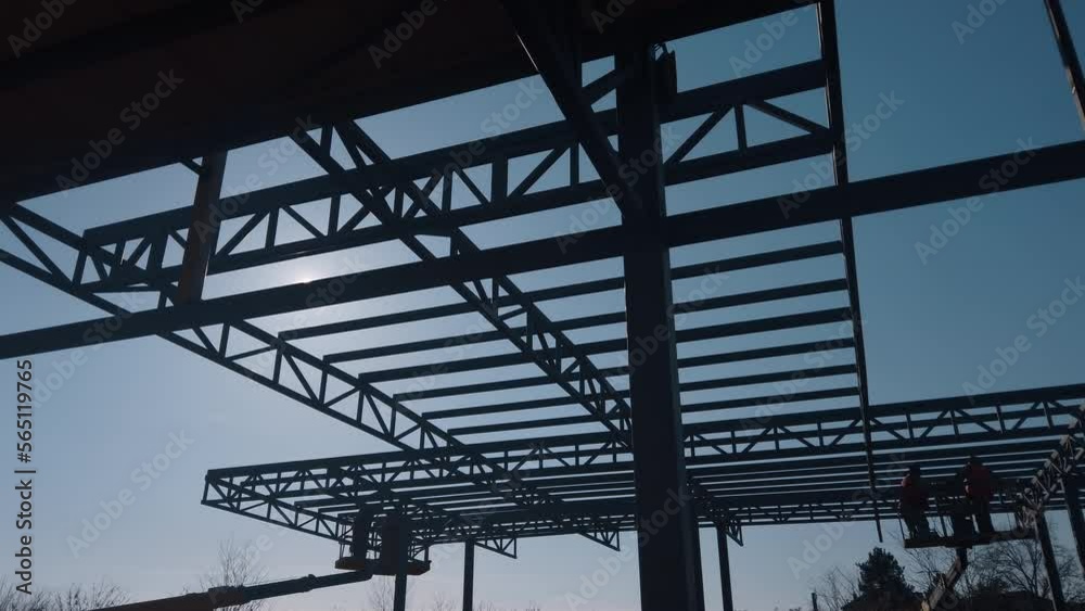 The steel structure is under construction. Installation of metal halls. Work at height. A sunny day at a construction site