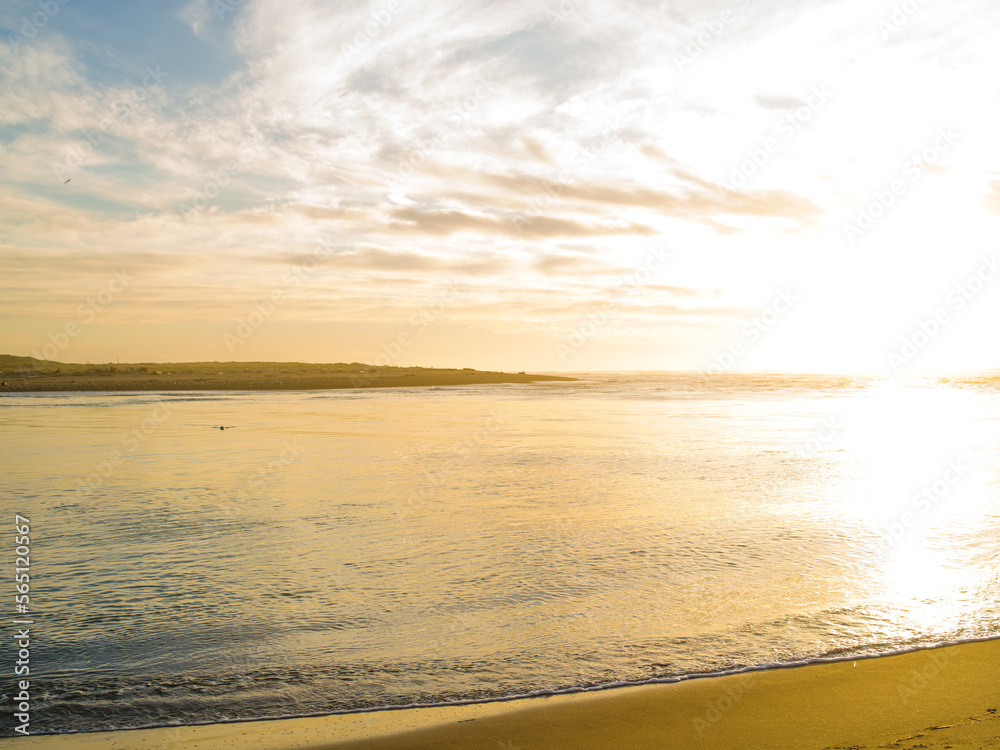 Obraz premium Beautiful sunrise on the sea coast. There are white fluffy clouds in the sky. The water is colored with pink rays of the rising sun. The beauty of nature, ecology, nature, weather.
