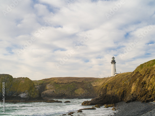 Lighthouse on a high hilly shore of the ocean. The sky is overcast. The beauty and majesty of nature. Navigation, storm, danger. There are no people in the photo.