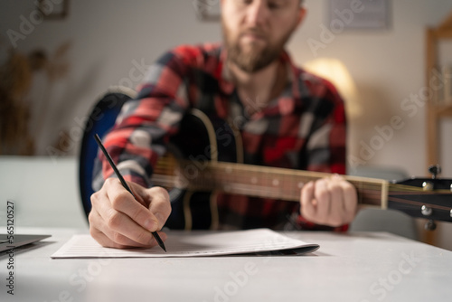 Man musician writing song with guitar at home, close up.