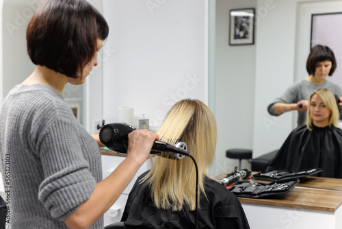 hairdresser dries hair with a hairdryer
woman in the salon. close-up.beauty and fashion concept