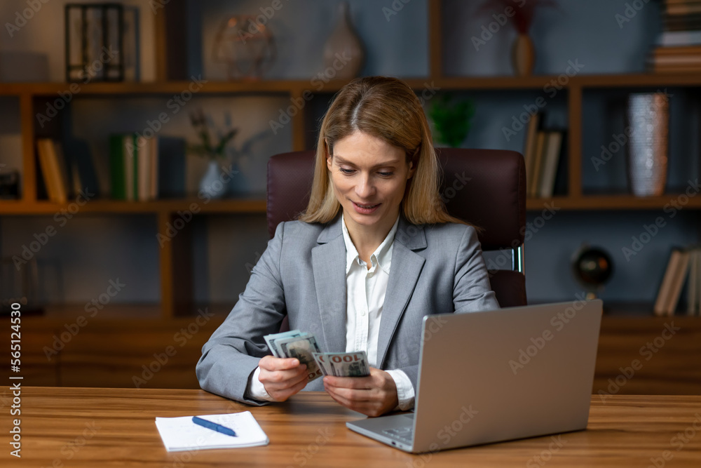 Fototapeta premium Successful business woman counting money at office desk in slow