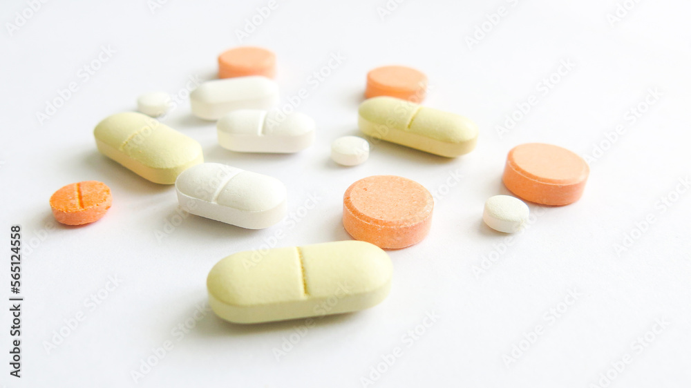 Assorted scattered pharmaceutical medicine pills and tablets in various colour and size isolated in white background