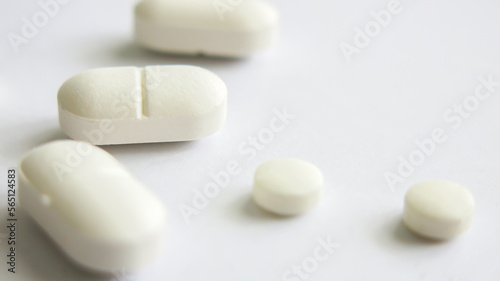 scattered pharmaceutical medicine white pills and tablets in white background