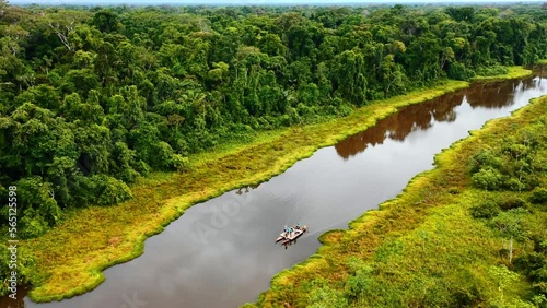Close aerial shot of the amazon river with a boat in the middle crossing in the morning hours and peruvian jungle nature in the background photo