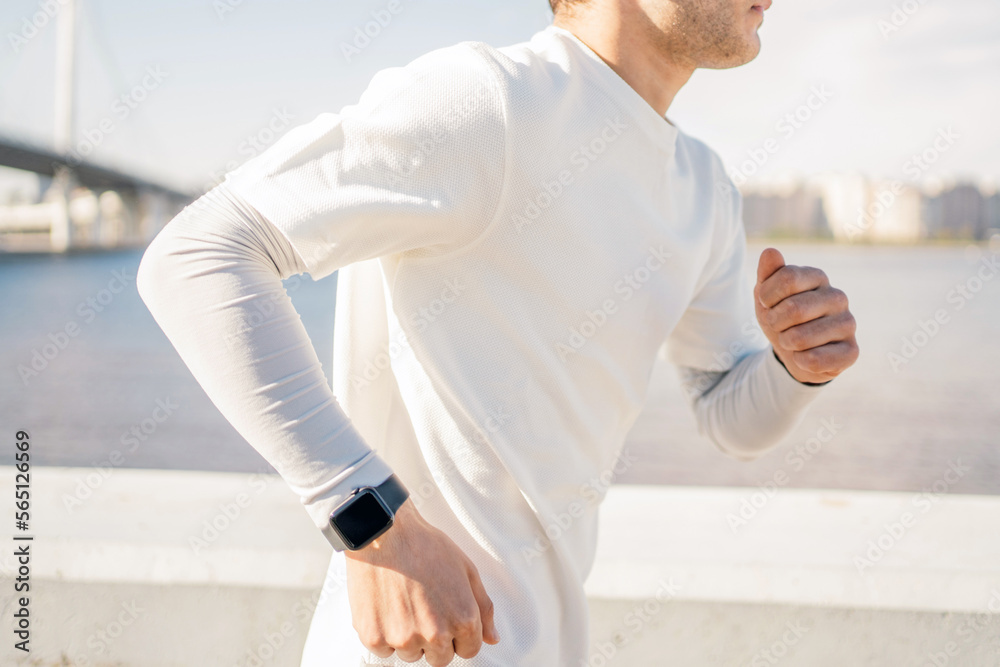 Using a smart fitness watch that measures the pulse and pressure on the arm. The trainer is a running sports man training in comfortable clothes.