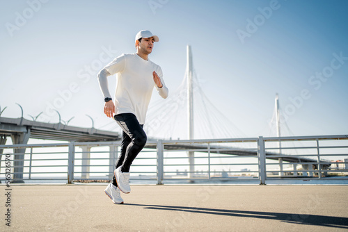 Trainer exercises developing cardio body. A male sports runner training in sportswear on the street.