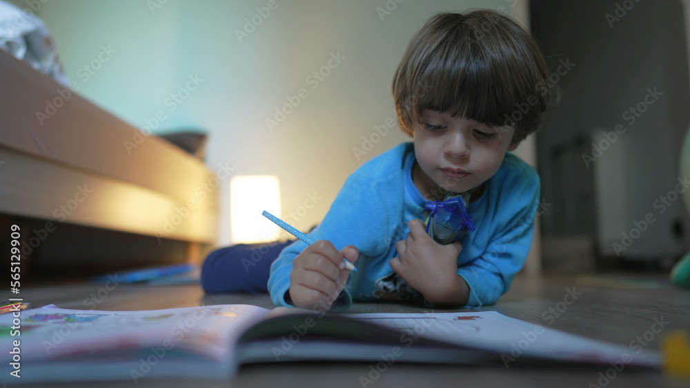 Childhood creative activity. Preschooler studying at home laying on floor. Young boy drawing on paper with coloring pen Childhood creative activity. Preschooler studying at home laying on floor. Young boy drawing on paper with coloring pen