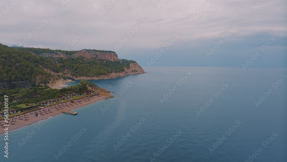 Natural landscape. Aerial drone view of a beach in a blue bay. Rocky coast. Green trees on the rocks.