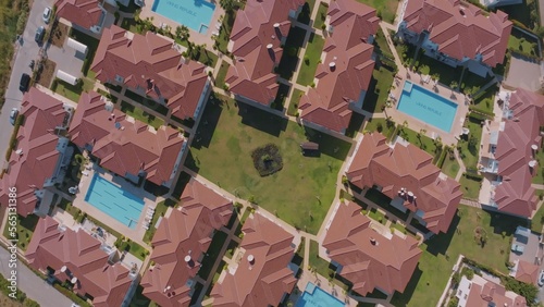 Aerial drone view of the hotel territory. Bungalow rooftops, swimming pools, green lawns and palm trees.