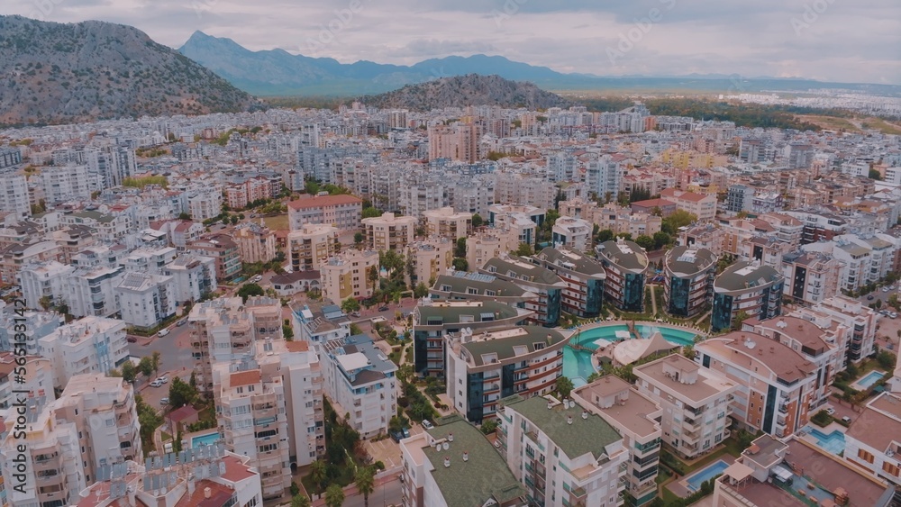 Aerial drone view over a big city against the backdrop of mountains. Top view of houses and hotels.