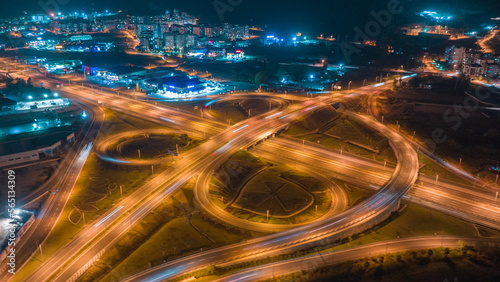 Aerial drone view multi-level intersection. Neon blue night lighting. Cars. City illumination. Road architecture. High quality photo