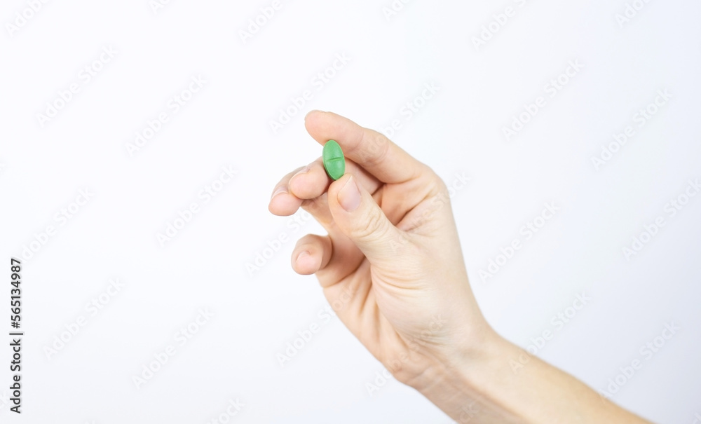 Green medical pill in human hand. Medicine treatment of diseases, viruses, antibacterial therapy, food supplement. White background Space for text Green medical pill in human hand. Medicine treatment of diseases, viruses, antibacterial therapy, food supplement. White background Space for text