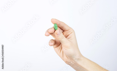 Green medical pill in human hand. Medicine treatment of diseases, viruses, antibacterial therapy, food supplement. White background Space for text