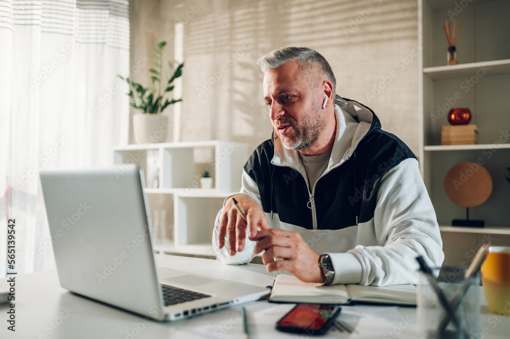 Middle aged man using a laptop while working in a home office Middle aged man using a laptop while working in a home office