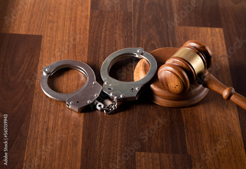 Gavel and handcuffs on wooden background