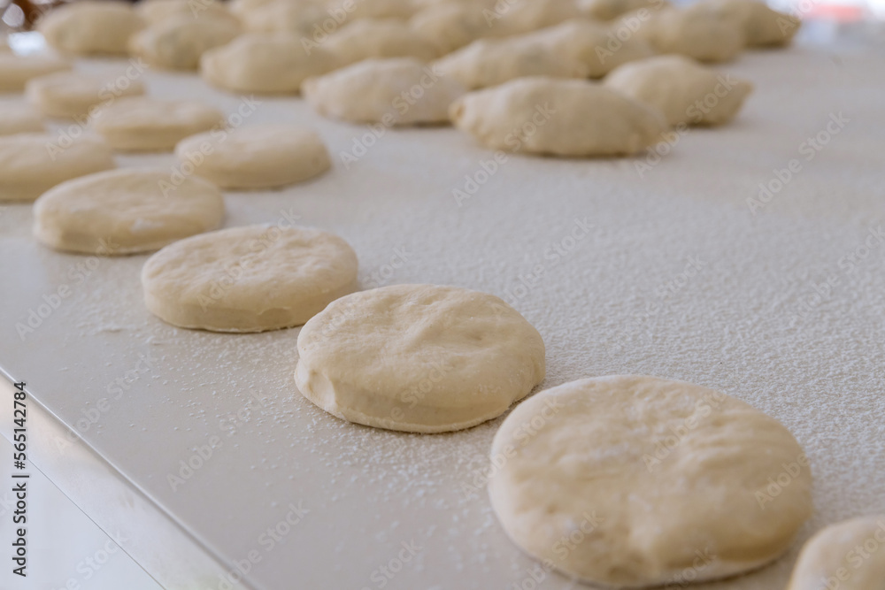 White countertop is used for preparing baking of buns with stuffing and donuts from yeast dough