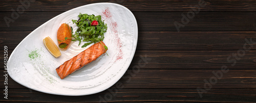 Grilled trout steak with lemon and arugula, on a plate, on a wooden background