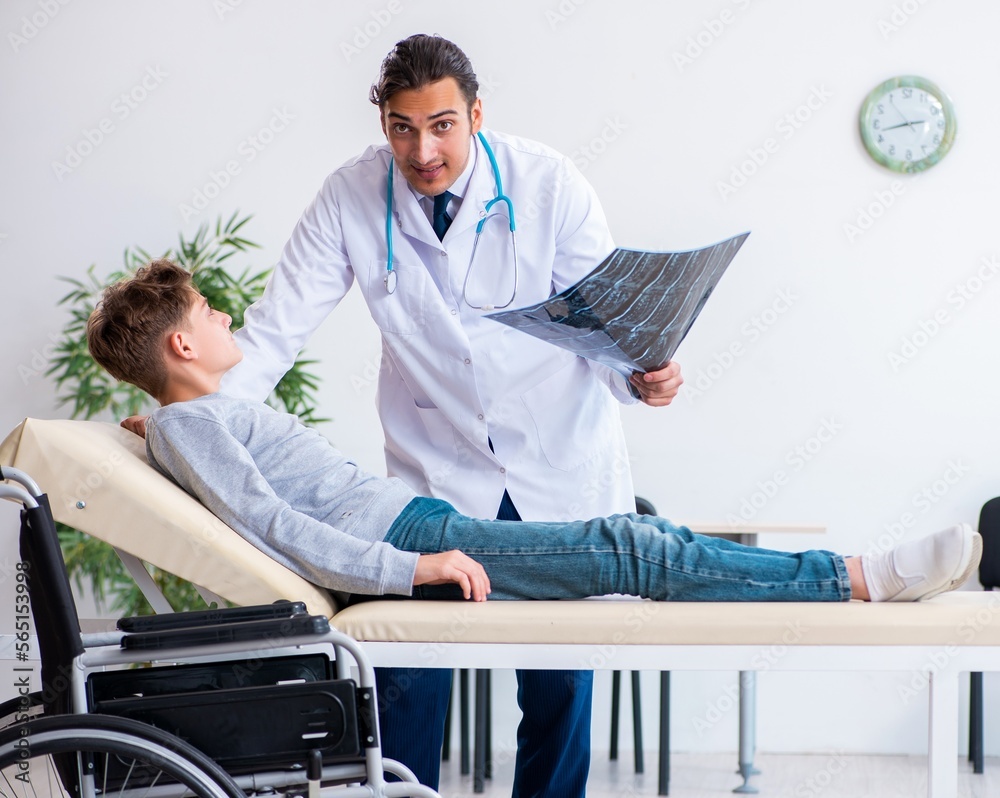Obraz premium Young male doctor pediatrist and boy in wheel-chair