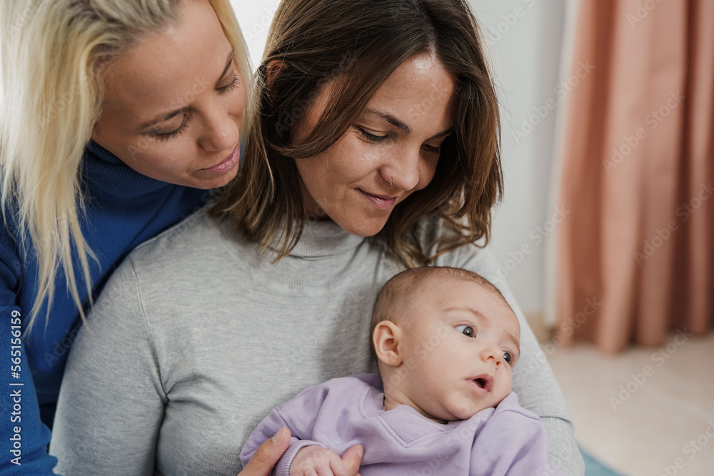 Loving lesbian couple having tender moment with baby together at home