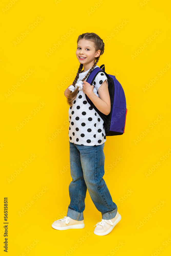A beautiful schoolgirl goes to school with a briefcase, a child with textbooks and notebooks goes to additional courses in a foreign language, a girl with a briefcase on an isolated yellow background