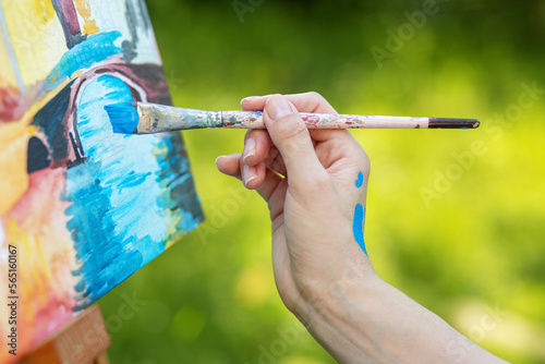 Closeup of female hand that draws picture in park. Art and hobby concept.