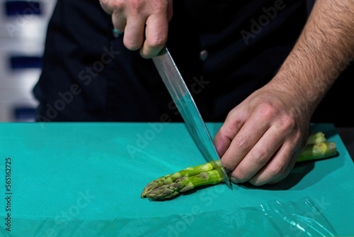 Foto The cook chopping asparagus. Chopping vegetables with a knife.