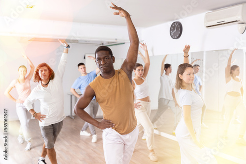 African-american man practicing active dance moves during rehearsal with group in dancing studio.
