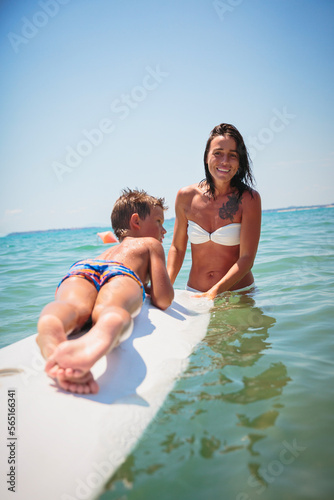 Mom with her teen son lying on a swimming board. Happy european family having fun floating on a swim board in the sea on a hot summer day © svittlana