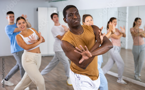 Canvas Print Group of young adult diverse active dancers in sportswear with crossed hands dur