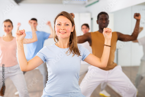 Energetic women and man performing modern dance in fitness studio