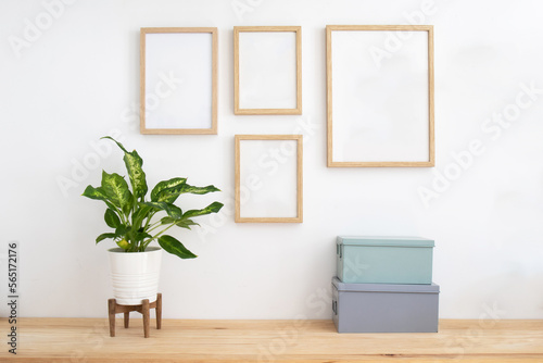 Gallery wall still life. Wooden desk table, houseplant, metal boxes and a set of empty picture frames mockup, Scandinavian decoration. Home office concept. Elegant space. 