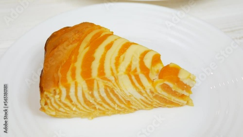 Cottage cheese casserole with pumpkin in a white plate on a white wooden table. Striped casserole with cheese and pumpkin. Cheese pumpkin cake. Cheesecake.