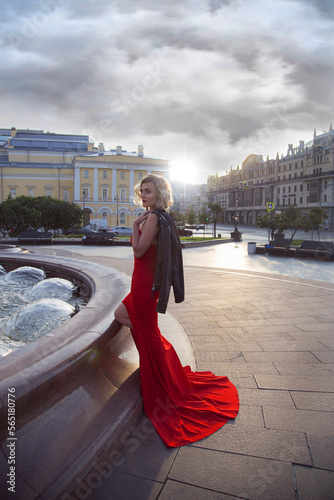 Photography Gorgeous woman in a sexy red dress walks in the center of Moscow in front of the theater