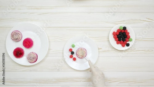 Rose shaped jelly dessert made from raspberries and cream in a white plate on a white wooden table. Chef cuts and taste the dessert.