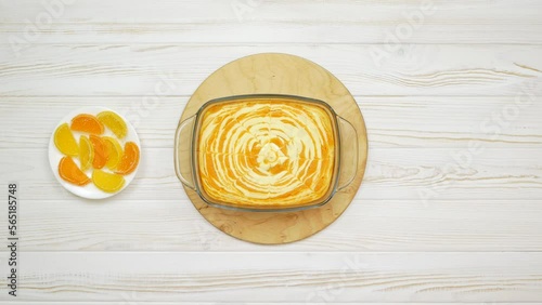 Cottage cheese casserole with pumpkin in a white plate on a white wooden table. Striped casserole with cheese and pumpkin. The chef puts a cheese pumpkin cake on the table.